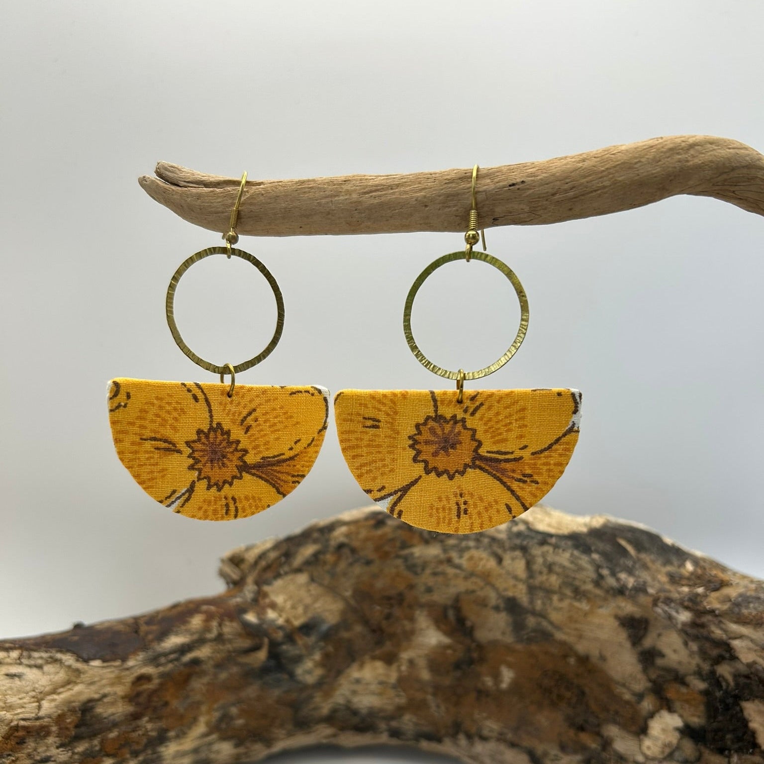 Orange vintage floral fabric earrings displayed on a branch with a white background